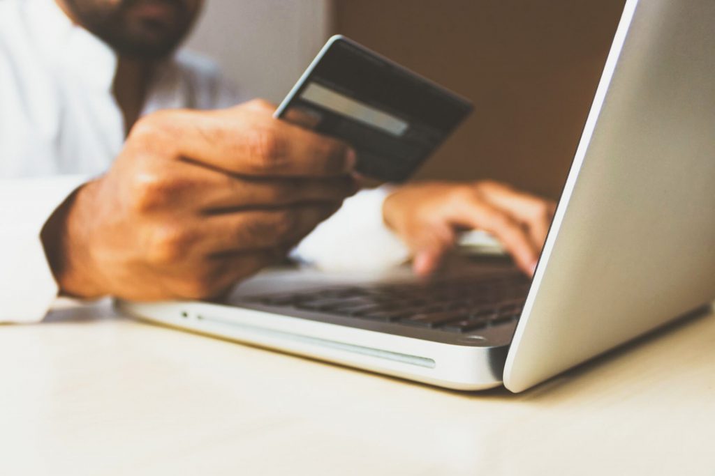 customer entering credit card information into computer while holding a credit card
